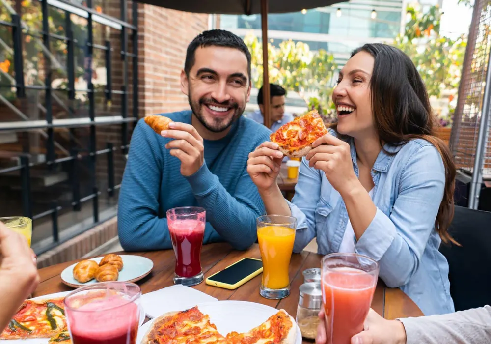 Two friends laughing over pizza at a restaurant