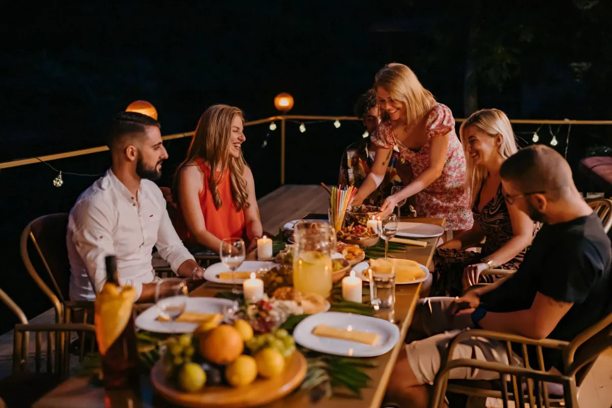 A long table of guests dining outdoors in the evening